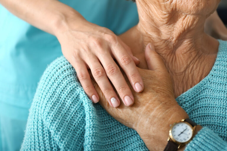 Doctor supporting elderly woman in clinic, closeup